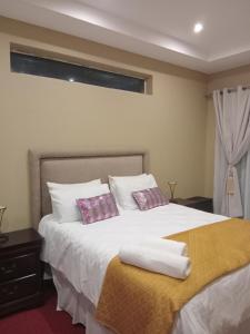 a bedroom with a bed with two pillows on it at Lovemoreheights Inn in Gqeberha +32 photos