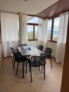 una mesa de comedor y sillas en una habitación con ventanas en Апартамент Созополски Залез, en Sozopol
