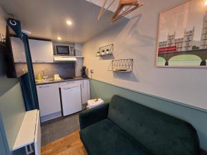 Una sala de estar con un sofá verde y una cocina. en 2G- Studio tout équipé avec cuisine proche Paris, en Issy-les-Moulineaux