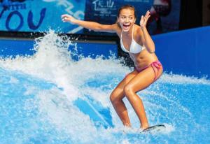 a girl riding a wave on a surfboard in the water at Fredika, modern 1br,Tripla Pasila prime location, gym, parking, train station near in Helsinki