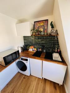 a small kitchen with white cabinets and a microwave at Studio Exotique Hyper-Centre Enghien 12min Paris in Enghien-les-Bains