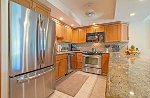 a kitchen with wooden cabinets and a stainless steel refrigerator at Kahana Sunset B4B in Kahana