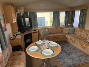ein Wohnzimmer mit Tisch und Couch in der Unterkunft 8 Berth Caravan in Chapel St in Chapel Saint Leonards