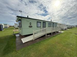 ein Gewächshaus mit einer Veranda auf einem Feld in der Unterkunft 8 Berth Caravan in Chapel St in Chapel Saint Leonards