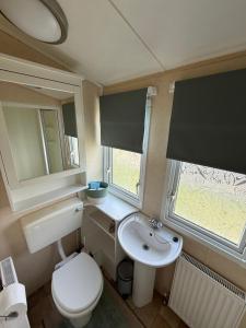 ein kleines Badezimmer mit Toilette und Waschbecken in der Unterkunft 8 Berth Caravan in Chapel St in Chapel Saint Leonards + 9 Fotos