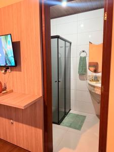 a bathroom with a shower with a television and a sink at Suíte Privativa in Florianópolis