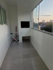 a room with a tv and a table and a window at Lindo apto 3 quartos todo novo in Torres