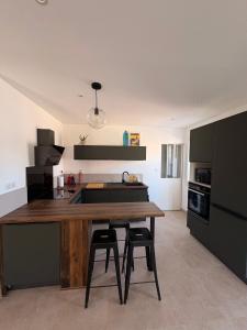 a kitchen with a wooden table and two bar stools at Maison individuelle en Provence in Pernes-les-Fontaines