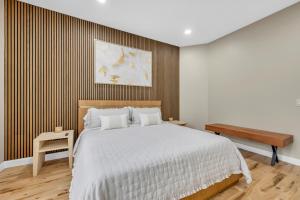 a bedroom with a large white bed and a bench at Coco in Farmington Hills