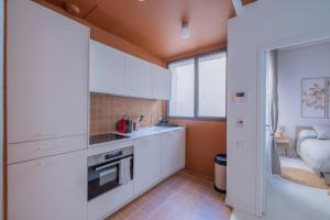 a kitchen with white cabinets and a bed in a room at Appartement Belle Lettre 7 in Aix-en-Provence