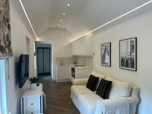 Boutique Cottage by Bishop's Stortford train station, easy to Stansted Airport & Parking في بيشوبس ستورتفورد: غرفة معيشة مع أريكة بيضاء ومطبخ