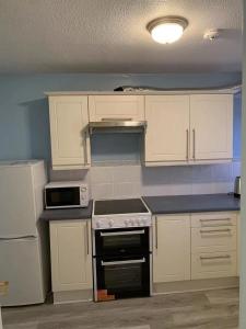 a kitchen with white cabinets and a stove top oven at Glasgow St George's Room in Glasgow