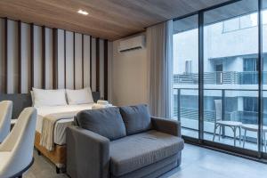 een slaapkamer met een bed, een bank en een raam bij Edifício New Time Apto 1406-Mandi Hospitalidade in Maceió +23 foto's