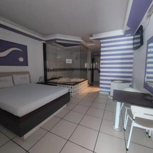 a bedroom with a bed and a desk and a sink at Hotel e Motel Rarus in Igaratinga