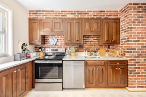 a kitchen with wooden cabinets and a brick wall at 3BR Home - Free Parking-WiFi Kitchen Laundry-Kids Friendly-Near DC & Downtown & Metro-Patio & Deck in Falls Church