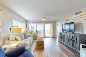 Oceanfront corner condo with sunrise-view balcony, pool & 1-minute walk to beach في فرناندينا بيتش: غرفة معيشة مع أريكة وتلفزيون