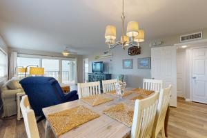 Oceanfront corner condo with sunrise-view balcony, pool & 1-minute walk to beach في فرناندينا بيتش: غرفة طعام وغرفة معيشة مع طاولة وكراسي