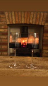 two wine glasses sitting on a table in front of a fireplace at Autumn Cottage in Filey +34 photos
