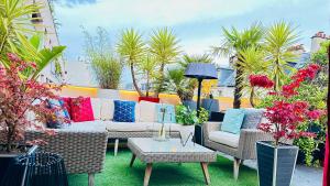 eine Terrasse mit einem Sofa, Stühlen und Pflanzen in der Unterkunft Private Rooftop Jacuzzi in La Celle-sous-Gouzon