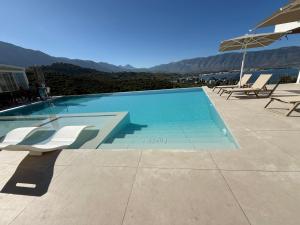 a swimming pool with two chairs and an umbrella at Cayo Exclusive Hotel in Vlorë