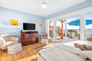 ein Schlafzimmer mit Bett und Fernseher und Balkon in der Unterkunft 3009 Ocean St E Beautiful Beachfront Condo w/ Ocean Views, Private Patio, Grill, & Free WiFi in Carlsbad