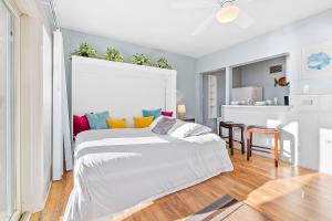 ein Schlafzimmer mit einem großen weißen Bett mit bunten Kissen in der Unterkunft 3009 Ocean St E Beautiful Beachfront Condo w/ Ocean Views, Private Patio, Grill, & Free WiFi in Carlsbad