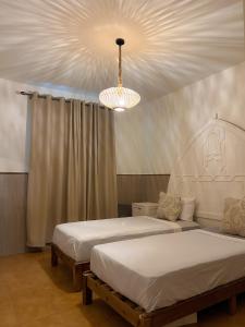 a bedroom with two beds and a chandelier at Casa Hugo in Chefchaouene