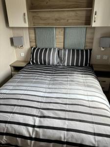 a bed with a striped comforter in a room at Fantasy island in Ingoldmells
