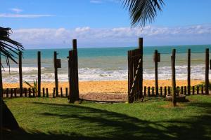 a fence on the beach with the ocean in the background at Vila Ohana Beira Mar - Caraíva in Caraíva