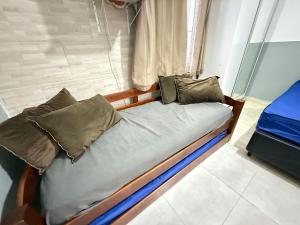 Cama pequeña en habitación con almohadas en Pies en la esquina de arena del fuerte VIII, en Praia Grande