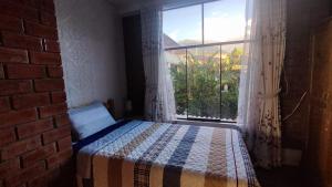 a bedroom with a bed and a large window at Hospedaje LLIKU WASI in Yungay