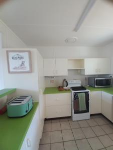 a kitchen with white cabinets and a stove top oven at Stay on Sooning in Nelly Bay