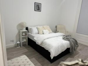 a bedroom with a large bed with white sheets at The Edgbaston Retreat in Birmingham