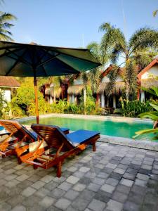 two chairs and an umbrella next to a pool at Edelweiss Homestay in Kuta Lombok