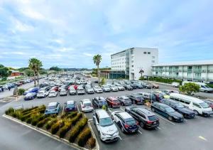 a parking lot full of cars in front of a building at JetPark Auckland Airport Hotel in Auckland