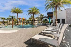 a row of white lounge chairs in front of a pool at Experience Luxury In Your 11 En-suites Mansion in Orlando