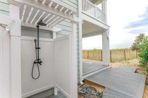 eine weiße Pergola auf einem Haus mit Terrasse in der Unterkunft Sojourn Dune Cottage Beach Front Bliss 3 BR 3 BA in Norfolk