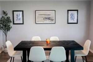 ein Esszimmer mit einem Tisch und weißen Stühlen in der Unterkunft Sojourn Dune Cottage Beach Front Bliss 3 BR 3 BA in Norfolk