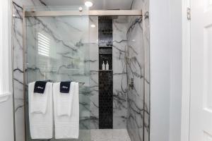 ein Bad mit einer Dusche und weißen Handtüchern in der Unterkunft Sojourn Dune Cottage Beach Front Bliss 3 BR 3 BA in Norfolk + 55 Fotos