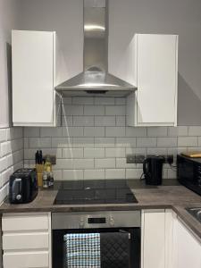 a kitchen with white cabinets and a stove top oven at Chic Maidstone getaway in Maidstone