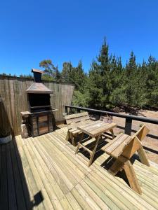 a wooden deck with a picnic table and a grill at forest house - Cabaña para 4 in Pichilemu