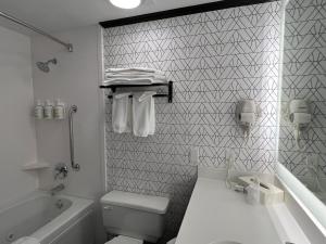 a white bathroom with a tub and a toilet and a sink at Sternwheeler Hotel & Conference Centre, Trademark by Wyndham in Whitehorse