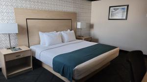 a hotel room with a large bed and a nightstand at Sternwheeler Hotel & Conference Centre, Trademark by Wyndham in Whitehorse