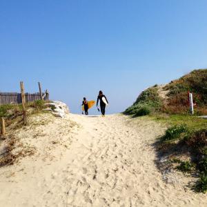 two people walking down a beach with their surfboards at Yado KONAMI in Shimoda