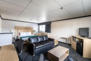 a hotel room with a bed and a couch and a tv at Sternwheeler Hotel & Conference Centre, Trademark by Wyndham in Whitehorse