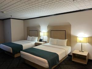 two beds in a hotel room with two lamps at Sternwheeler Hotel & Conference Centre, Trademark by Wyndham in Whitehorse