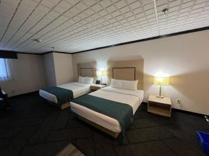 a hotel room with two beds and two lamps at Sternwheeler Hotel & Conference Centre, Trademark by Wyndham in Whitehorse
