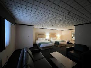 a hotel room with two beds and a couch at Sternwheeler Hotel & Conference Centre, Trademark by Wyndham in Whitehorse