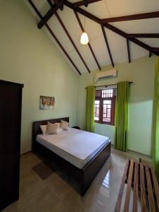 a bedroom with a large bed with green curtains at Airport Blessings Villa in Katunayaka