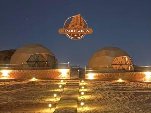 a group of domes with a sign that reads desert wings at RUM WINGS BUBBLES lUXURY CAMP in Wadi Rum